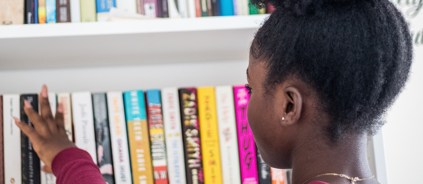 Young girl looking at bookshelf