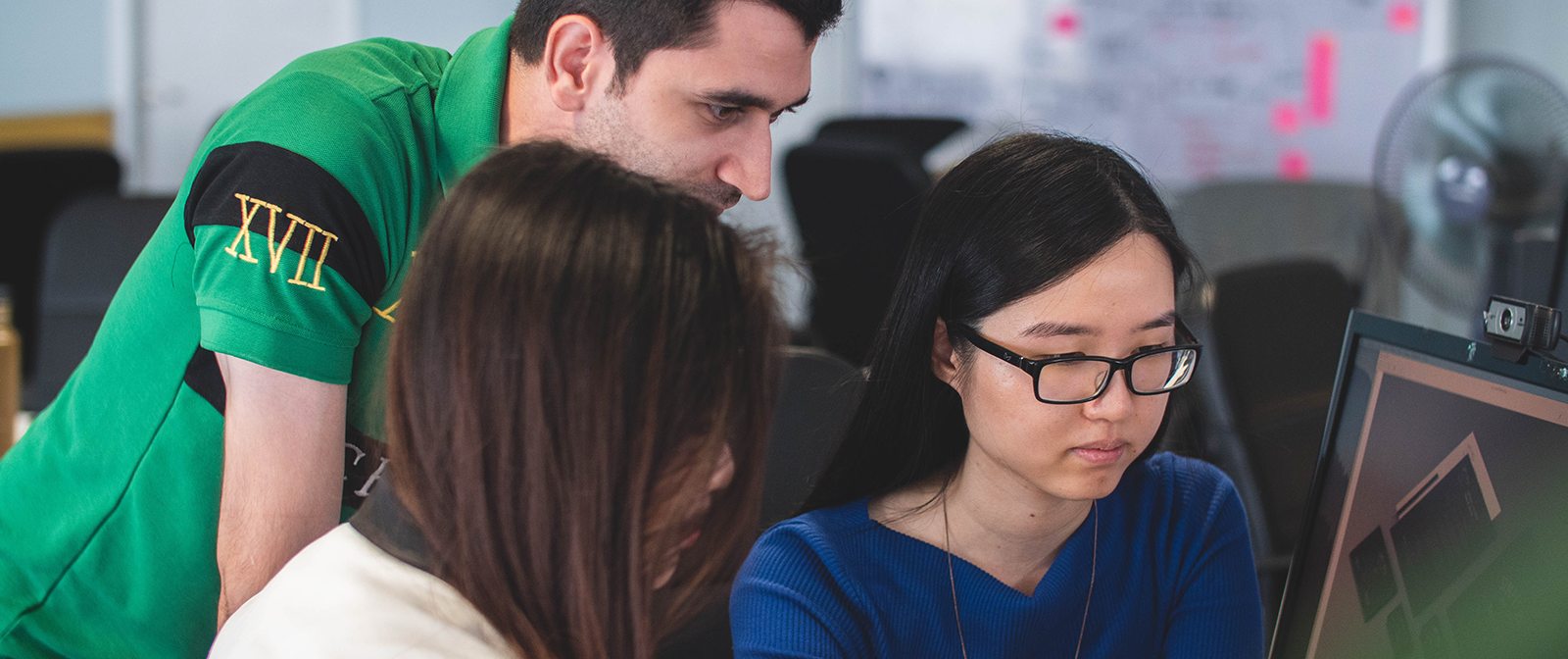 Man assisting two women on computer