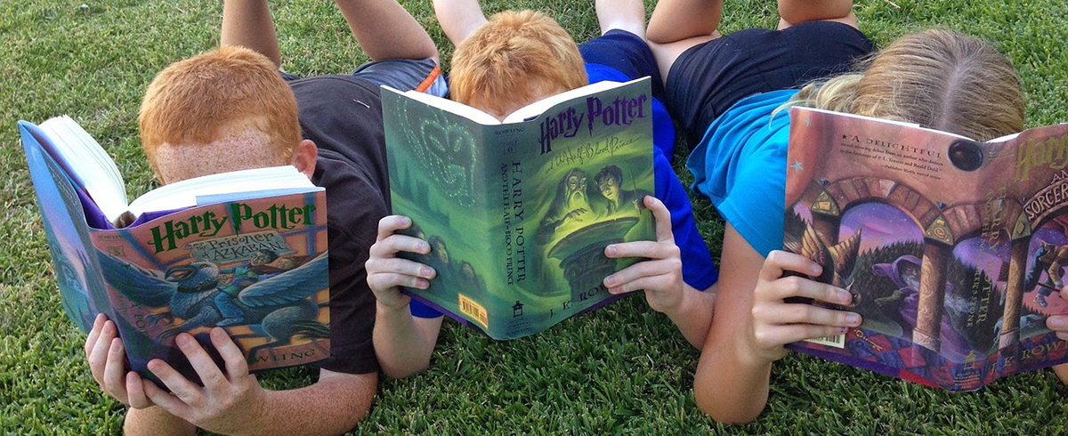 Three children reading Harry Potter books