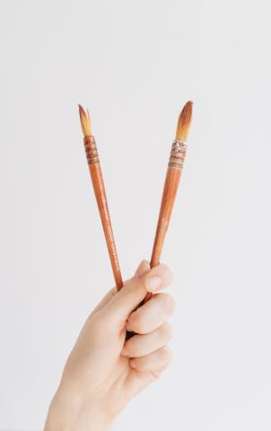 Two paintbrushes being held