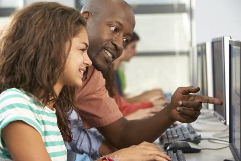 Teacher helping student at computer