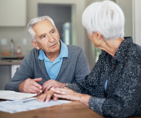 Two seniors talking across a table