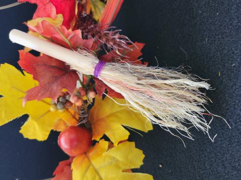 photo of a small mini broom resting against fall leaves