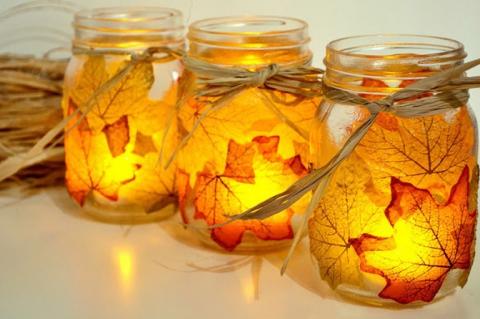 photo of three mason jars covered in orange fall leaves