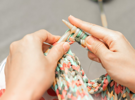 close up of hands knitting with wooden knitting needles