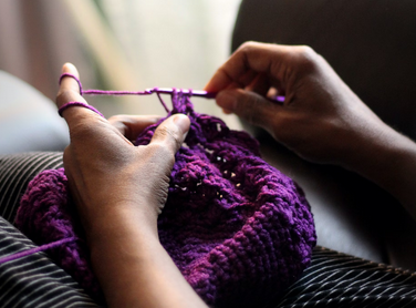 close up of hands crocheting with purple yarn