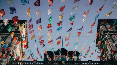 photo of paper bunting hanging between stone buildings in Mexico