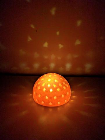 photo a 3D printed half circle with star holes over a light source projecting star shaped light on the wall