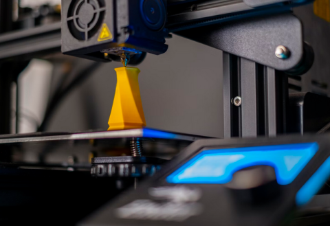 photo of a 3D printer printing an orange abstract art piece