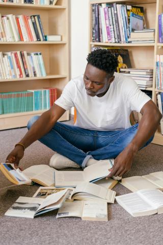 Man sitting on floor surrounded by open books