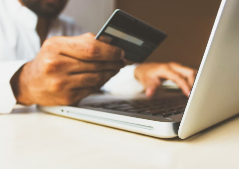 close up of someone holding a credit card and typing on a laptop