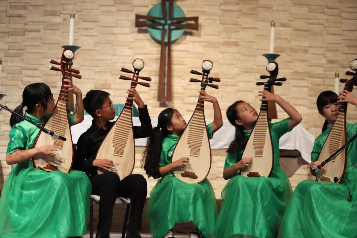 A group of young people playing pipa, a stringed instrument