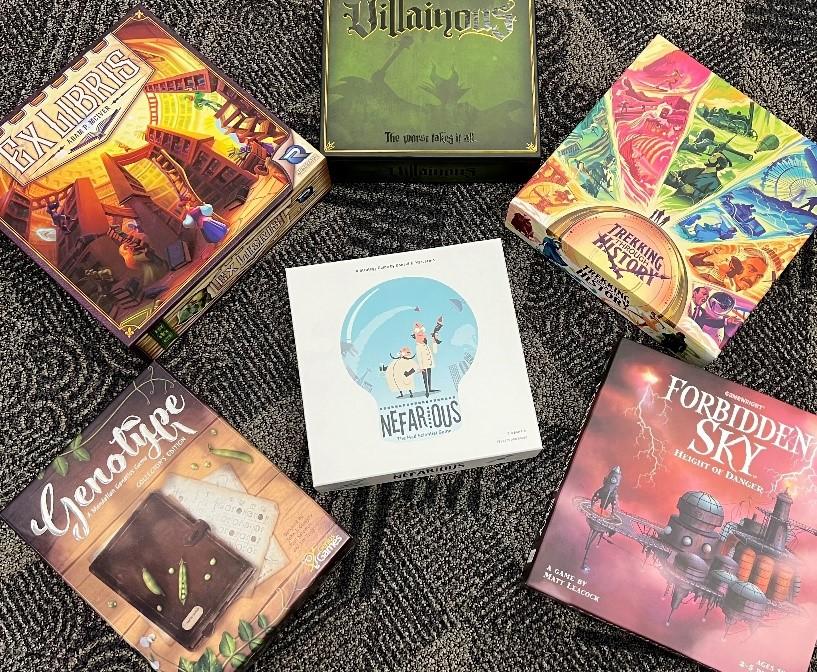 five board game boxes encircling a sixth board game box 