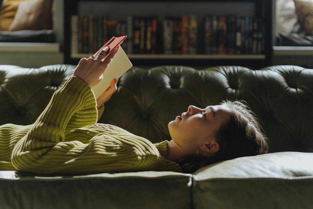 Woman lying on couch reading