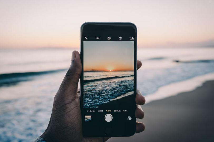 someone taking a photo of a scenic beach with a phone