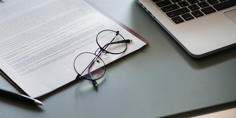 Forms on a clipboard with a pair of reading glasses