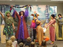 Actors from HGO's Opera to Go group perform a scene from Rapunzel in front of children sitting on the floor.